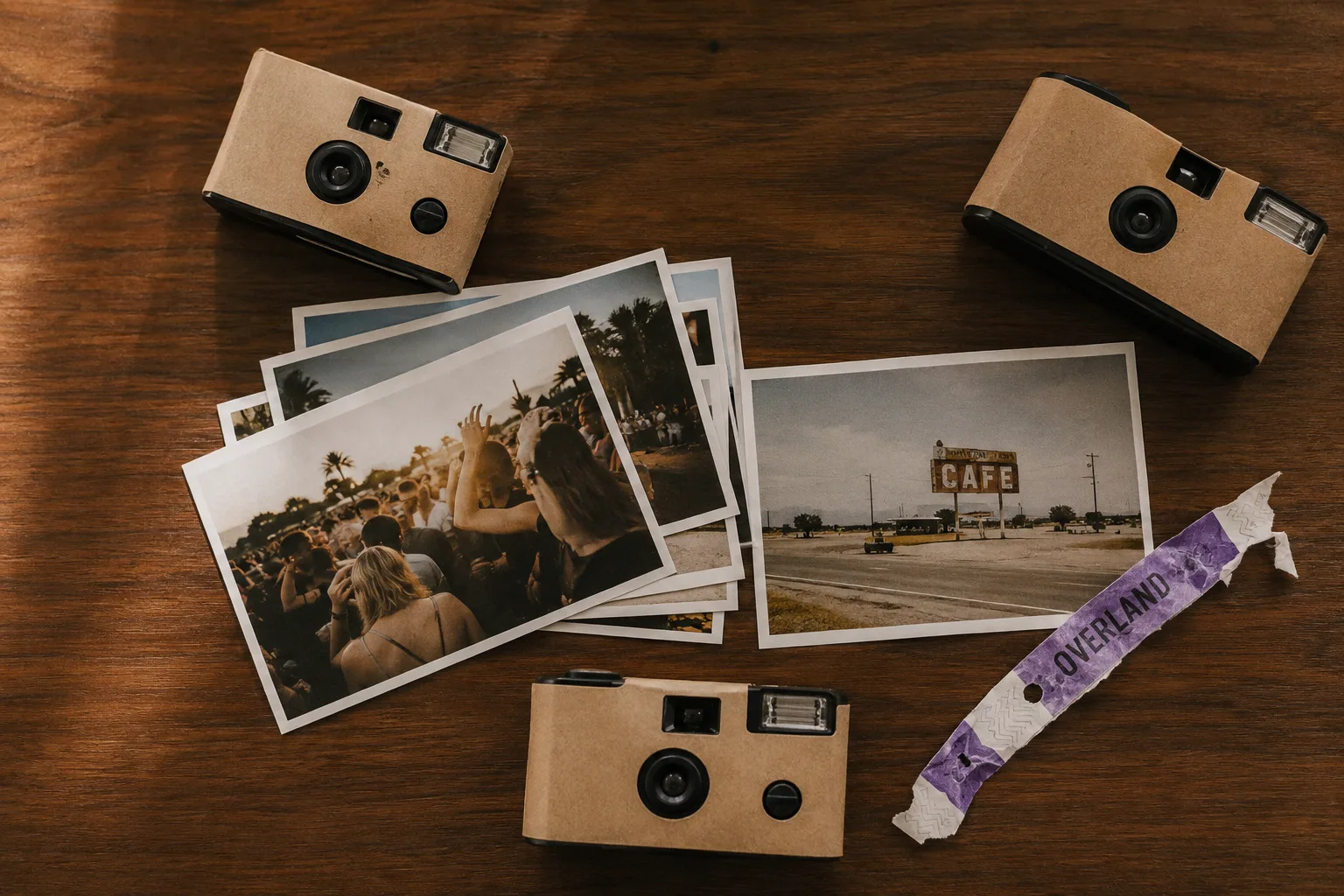 Disposable cameras and printed photographs scattered on a warm wood surface