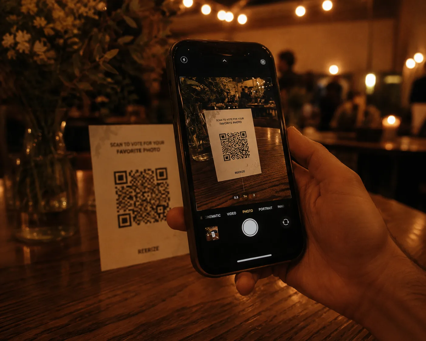 A hand holding a smartphone at a warm, softly-lit event